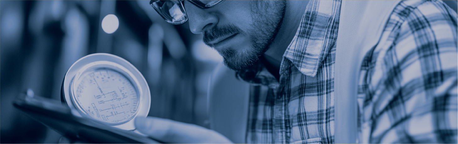 Mann med hjelm som noterer observasjoner under inspeksjon av rørsystem.